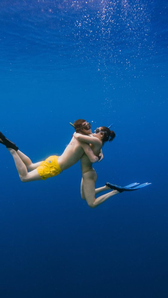A couple embracing underwater, showcasing love and adventure in a vibrant ocean setting.