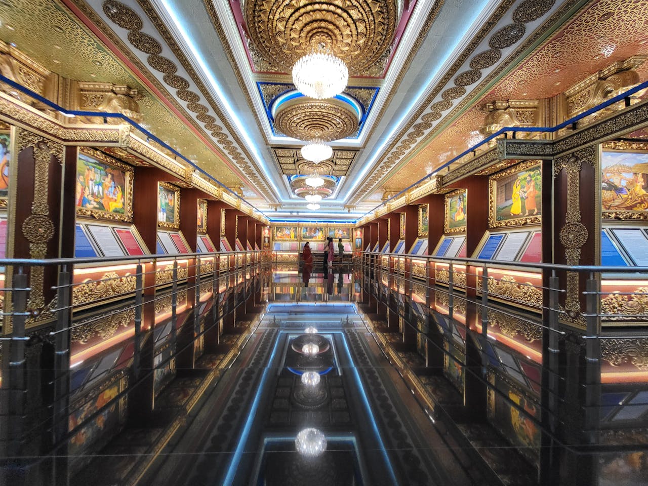 about-02 Beautifully decorated corridor with golden motifs and chandeliers, showcasing lavish interior design.